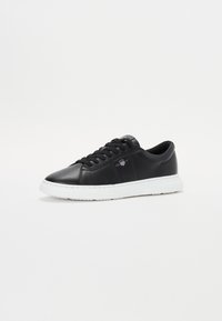 Sneaker din piele neagră cu vârf rotund, talpă din cauciuc alb și șireturi negre. Prezentă detalii cusute și un mic logo pe lateral.