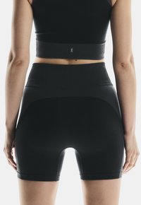 Schwarze, gerippte Sportshorts mit hohem Bund, die einen Ausschnitt an der Rückseite und eine glatte Textur aufweisen.