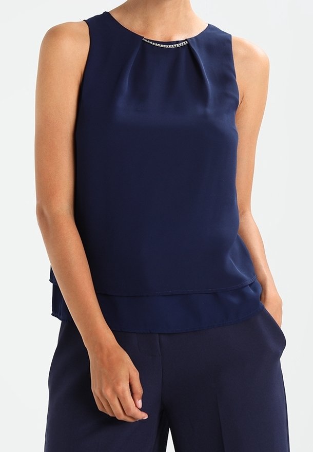 Mörkblå ärmlös topp i mjukt tyg med rund halsringning och en diskret veckdetalj samt en dekorativ metallackcent.