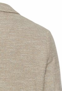 Beiger strukturierter Blazer aus einem gewebten Stoff mit einem geschlitzten Kragen und subtilen Karomuster. Es sind keine sichtbaren Verschlüsse vorhanden.