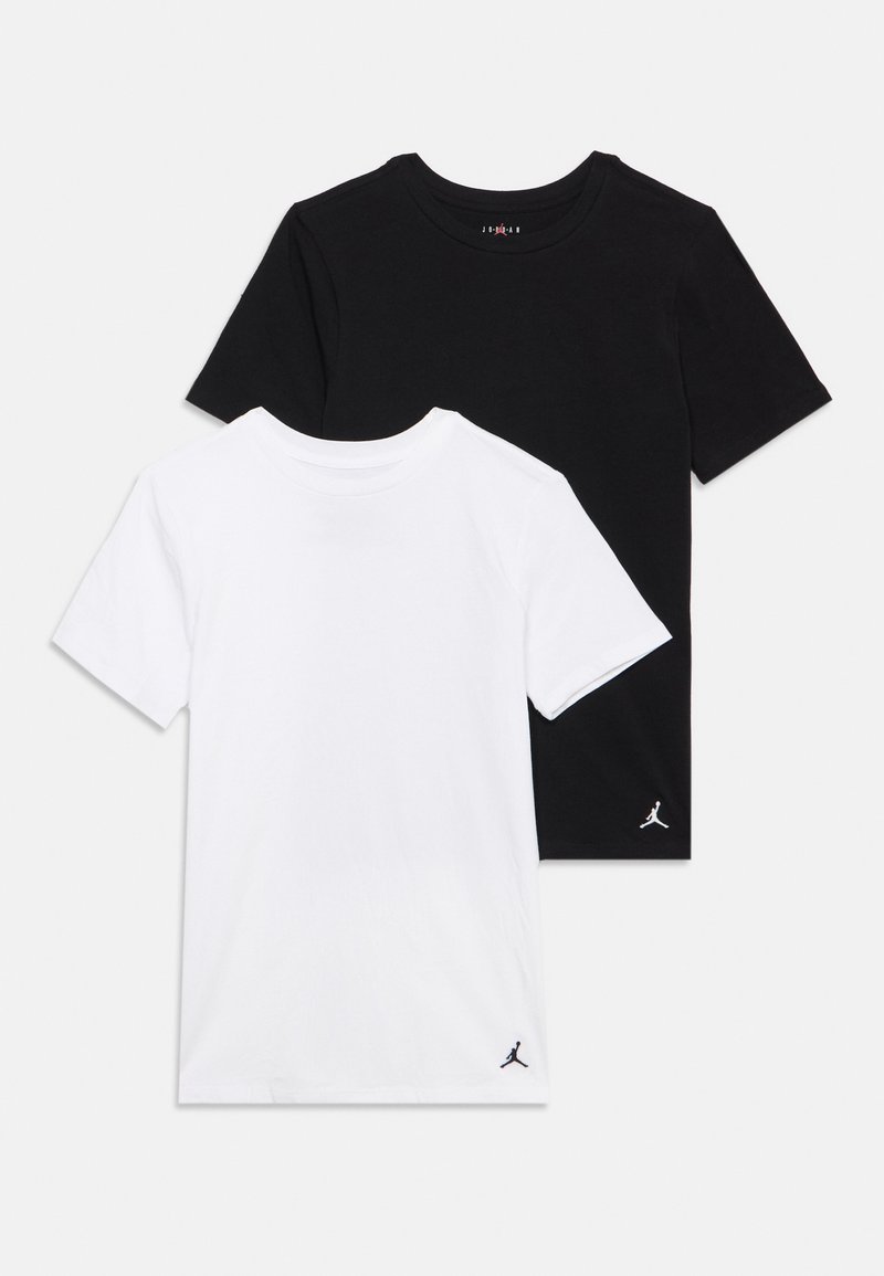 Deux t-shirts unis à manches courtes, un noir et un blanc, chacun avec un petit logo Jumpman près de l'ourlet inférieur.
