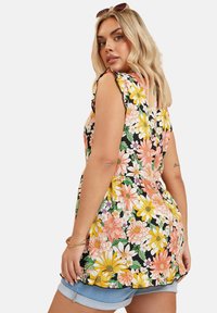 Ärmelloses Blumenshirt mit Rüschenkanten; schwarzer Grund mit bunten Gänseblümchen und Blumenmustern; leichtes Material.