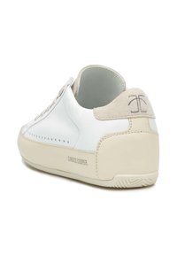 Sneaker bianco in pelle con tallone in camoscio beige e design perforato. Presenta un logo sul tallone e una suola in gomma testurizzata.