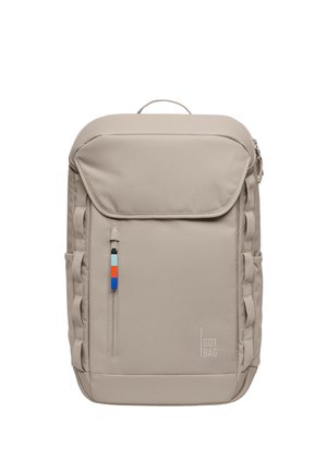 Zaino rettangolare beige con patta superiore, tasca frontale con zip e tirante multicolore, cinturini laterali e logo "GOT BAG" in basso a destra.