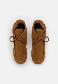 Stivaletti in suede marrone con punta rotonda, design con lacci, dettagli cuciti e suola in gomma texturizzata per una buona aderenza.