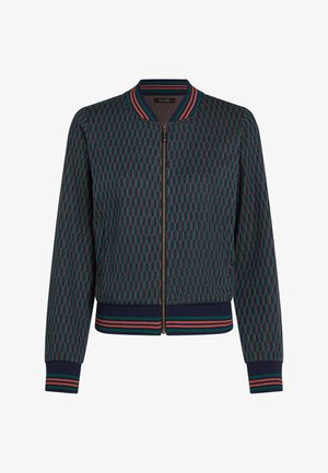 Bomber jacket dengan pola sarang lebah hijau gelap dan biru navy, kerah, manset, dan hem berjalur merah dan hijau, serta ritsleting depan.
