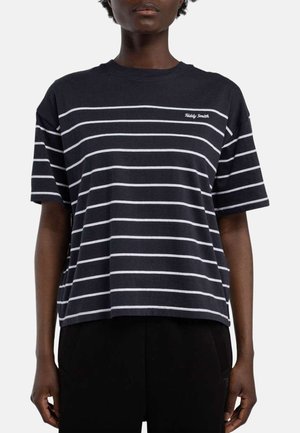 Personne portant une chemise noire à manches courtes avec des rayures blanches horizontales et le texte « Teddy Smith » sur la poitrine.