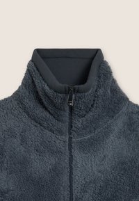 Giacca di felpa grigia con collo alto e chiusura a zip. Tessuto morbido e texturizzato con polo a coste in contrasto.