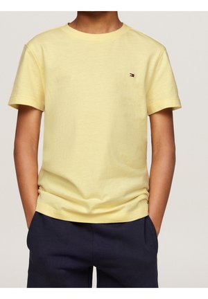 Gul T-shirt med korte ærmer lavet af blød bomuld, med en lille logo på venstre bryst. Kombineret med mørkeblå bukser.