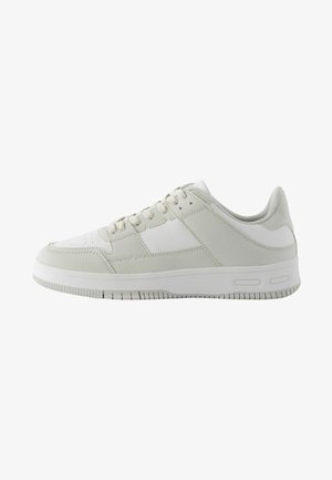 White athletic sneaker with a textured leather upper, smooth accents, lace-up design, and a rubber sole featuring horizontal grooves.