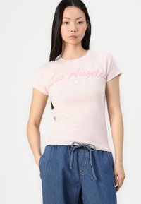 Ljusrosa t-shirt med kort ärm och grafik med "Los Angeles" samt fem stjärnor. Mjuk tyg, figurnära design, rundad halsringning. Matchas med denimbyxor.