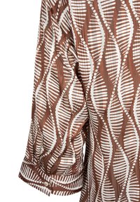 Tessuto marrone con motivo geometrico a foglia lineare e puntinata bianca su un polsino di camicia a maniche lunghe con chiusura a bottone.