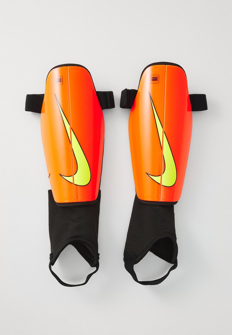Nike sääreprotectoreid, millel on ereoranž kõva kest ja suur neoonkollane logo. Komplektis on mustad kangaslelud jalalaba avadega.