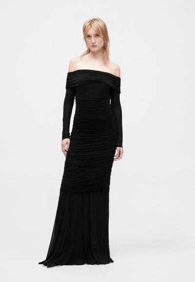 Vestido preto sem mangas, com mangas longas, apresentando tecido franzido para textura, um corpete ajustado e uma saia até ao chão.