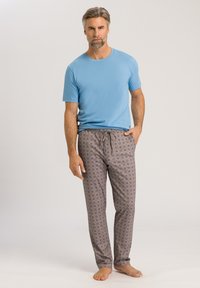 Lichtblauw t-shirt met korte mouwen, gecombineerd met bruin gestreepte pyjamabroek met bloemenpatroon. De broek heeft een elastieken tailleband met trekkoord.