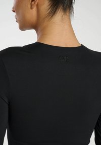 Czarny dopasowany top z długim rękawem i okrągłym dekoltem, wykonany z teksturowanej tkaniny. Posiada subtelne haftowane logo "S/B" na plecach.