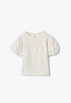 Roomkleurig kinder T-shirt met korte mouwen, pofmouwen en een vierkant kantpatroon aan de voorkant.