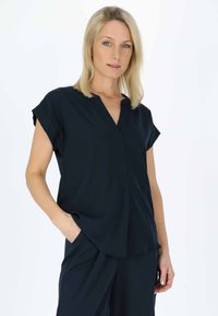 Marineblaues Kurzarmoberteil mit V-Ausschnitt, aus leichtem Material, lockerer Passform und seitlichen Taschen, das über ein einfaches, ungemustertes Design verfügt.