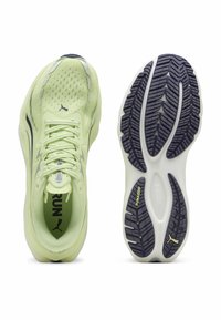 Ανοιχτοπράσινο παπούτσι τρεξίματος με επάνω μέρος από δίχτυ και κορδόνια, εμφανιζόμενο από πάνω και τη σόλα με μαύρο πέλμα και την επωνυμία "PUMAGRIP".