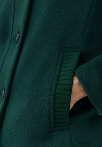 Grüne Wollmischung Jacke mit weicher Textur, klassischem Knopfverschluss und gerippten Akzenten an den Taschen für zusätzlichen Detail.