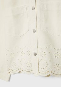 Lichtgekleurde denim blouse met zilverkleurige knoppen, voorzien van twee zakken aan de voorkant en een golfvormige onderkant met bloemenborduursels.