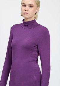 Lila, langärmeliger Rollkragenpullover, aus einem glatten, dehnbaren Stoff gefertigt. Verfügt über ein enges Design und einen hohen Kragen. Einfacher und eleganter Stil.