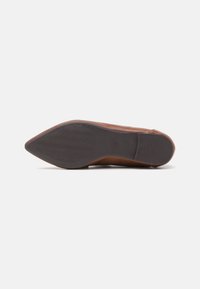 Brązowe skórzane buty z wąskim czubkiem, z wzorzystą gumową podeszwą i gładką górną częścią. Minimalistyczny design, bez widocznych akcentów.