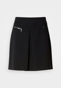 Jupe noire longueur genou avec pli avant, ceinture diagonale, poche zippée en métal sur la gauche et petit anneau en métal sur le côté droit.