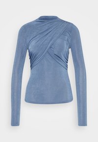 Sininen, pitkähihaisen paita pehmeästä, teksturoidusta kankaasta. Siinä on kiertynyt etumalli ja istuva siluetti sekä pyöreä pääntie.