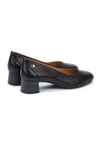 Chaussures en cuir noir avec des détails perforés, bout rond et un petit talon carré. L'intérieur est doublé d'un cuir lisse marron.