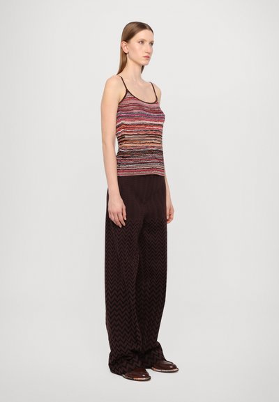 Top de tip tank multicolor cu dungi, având bretele subțiri, asortat cu pantaloni largi cu model în zigzag maro. Texturi netede pe întreaga suprafață.