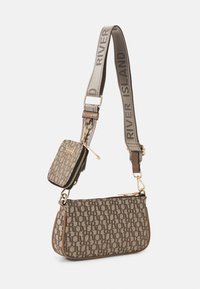 Hnědá kabelka přes rameno s vzorem a zlatým kováním, odnímatelným malým zipovým pouzdrem a popruhem s nápisem „RIVER ISLAND“. Povrch s texturou.