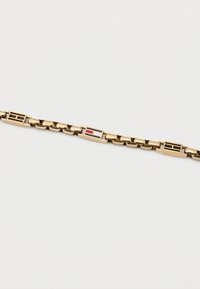 Βραχιόλι με χρυσή επίστρωση και ορθογώνιες ενότητες, διακοσμημένο με κόκκινες, λευκές και μαύρες σμάλτο λεπτομέρειες σε απλό λευκό φόντο.