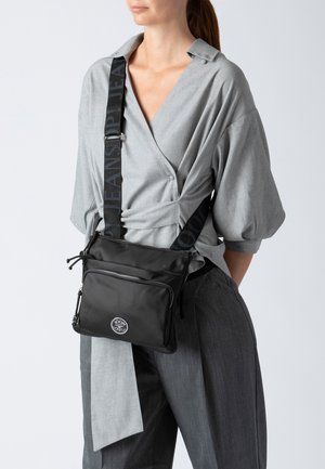 Borsa a tracolla nera con finitura liscia, dotata di una patch con logo, due scomparti con zip e una tracolla regolabile con stampa del logo.