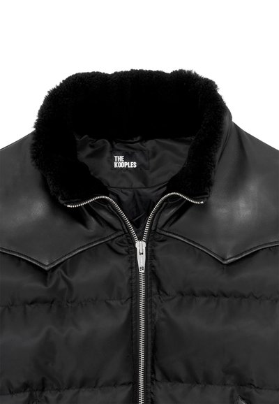 Schwarze Steppjacke mit Kunstfellkragen, Metallreißverschluss und Schulterakzenten, mit glatter, gesteppten Textur und Logoschild.