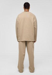 Beige oversized sweatshirt en bijpassende broek van zachte stof, met een relaxte fit, geribde boorden en een minimalistisch ontwerp.