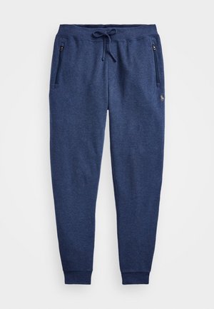 Pantalon de survêtement bleu marine avec taille élastique, cordon, poches latérales zippées et petit logo brodé sur la partie supérieure de la cuisse.
