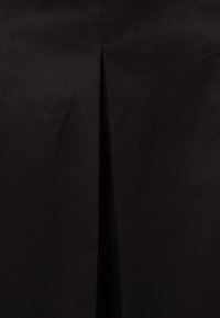 Zwarte stoffen rok met een subtiele glans, met een design van een middenplooi. Gemaakt van zachte materialen, met een gladde textuur en minimale stiksels.