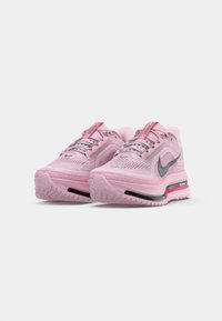 Une paire de baskets de course Nike Air Max rose avec des logos swoosh gris, des tiges en mesh et des semelles à coussin d'air noir et rose sur fond blanc.