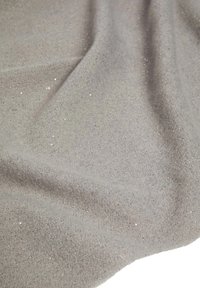 Tessuto grigio drappeggiato in modo uniforme, che mette in mostra una consistenza morbida con una leggera lucentezza e piccole macchie sparse, creando un effetto visivo delicato.