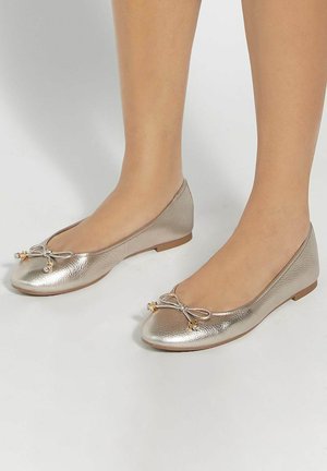 Ballerines en métal doré avec une finition texturée, bout rond, et détail nœud à l'avant avec de petites accents. Talon plat.