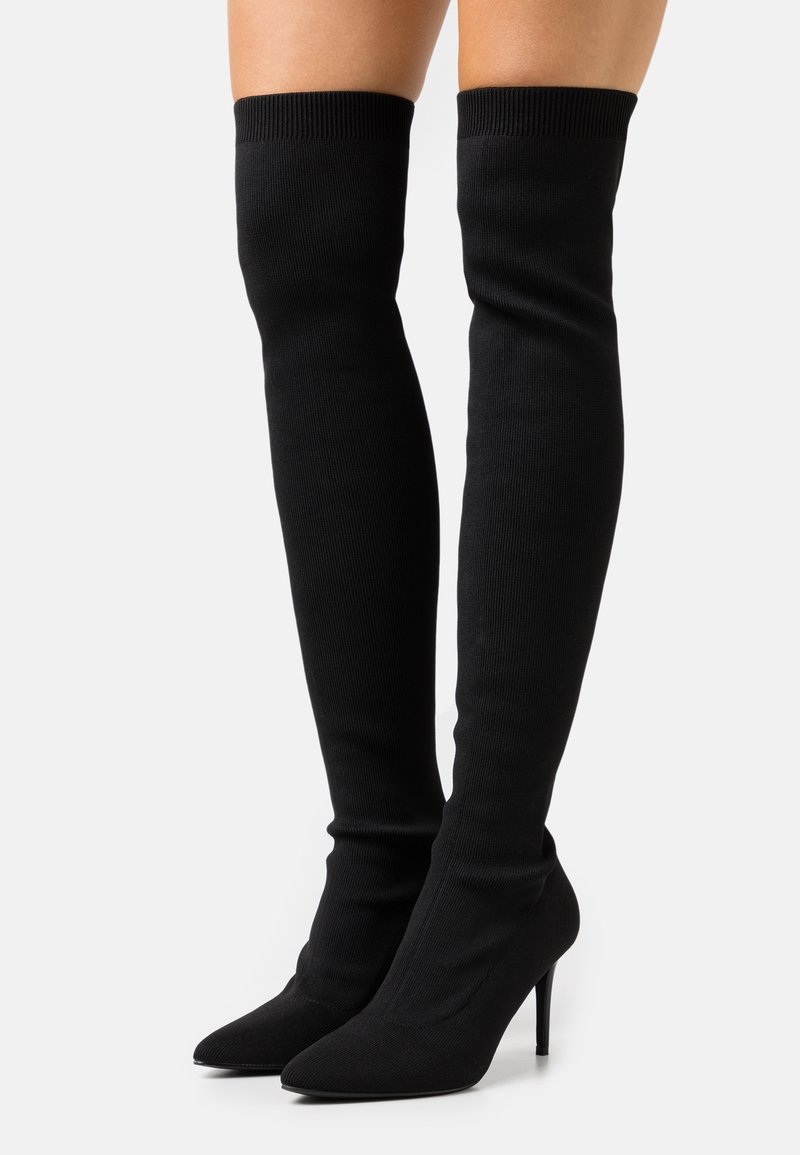 Černé elastické boty do výšky kolen s špičatou špičkou a jehlovým podpatkem. Klasický žebrovaný vršek pro bezpečné uchycení, hladká textura po celé délce.