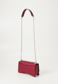 Borsa a tracolla in pelle rossa con un design curvo, dotata di una tracolla in catena dorata e un motivo floreale in rilievo sulla superficie.