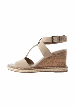 Sandale compensée en daim beige avec bride à la cheville, boucle noire, talon compensé en liège et bordure tressée sur la semelle.