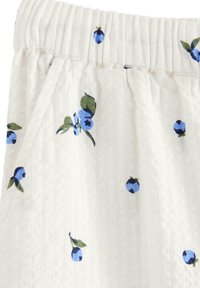 Witte stof met een blauw bloemenpatroon met kleine bosbessen en groene bladeren. Elastische tailleband met geplooide textuur. Zachte, lichte stof.