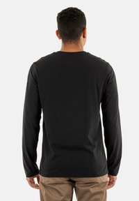 Zwarte katoenen t-shirt met lange mouwen en een ronde hals, minimalistische stiksels en een gladde textuur, bekeken vanuit de achterkant.