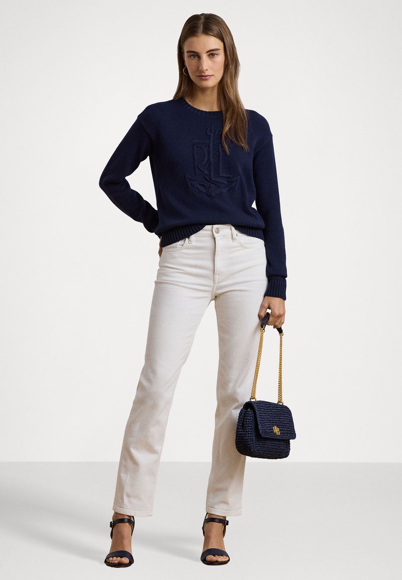 Μπλούζα ναυτικού στυλ με υφή άγκυρας, εκρού παντελόνια ίσια γραμμή και τσάντα πλέξη σε ναυτικό χρώμα με λεπτομέρειες χρυσού αλυσίδας. Μαύρες ανοιχτές γόβες.