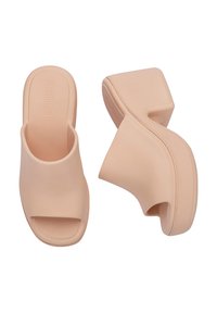Platformowe klapki w kolorze brzoskwiniowym, wykonane z gładkiego plastiku. Posiadają otwarty nosek oraz masywny, wyprofilowany obcas dla lepszej stabilności.