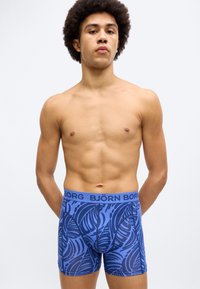Μπλε μπόξερ σορτς με σχέδιο από φύλλα, ελαστική μέση με ετικέτα "BJÖRN BORG", απαλή υφή, εφαρμοστή σχεδίαση και μήκος μέχρι το μέσο του μηρού.