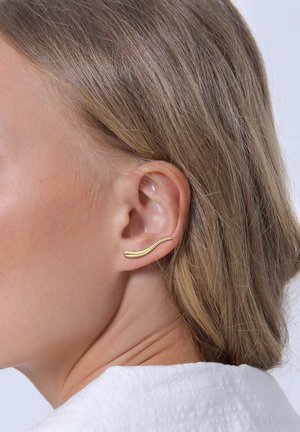 Goldfarbener Ohr-Cuff mit wellenförmigem Design, das entlang des äußeren Ohrs positioniert ist, glatte Textur, minimalistischer Stil und keine sichtbaren Verschlüsse.